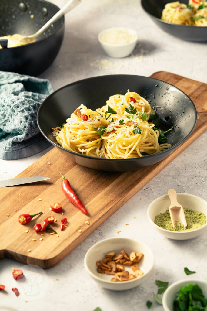 Spaghetti aglio e olio - der italienische Klassiker, auf dem Teller mit Chili, gerösteten Knoblauchscheiben und Petersilie