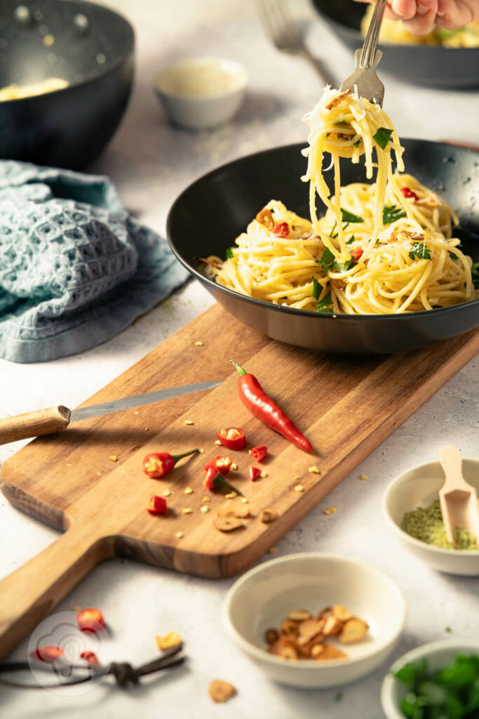 Spaghetti aglio e olio - der italienische Klassiker, auf dem Teller mit Chili, gerösteten Knoblauchscheiben und Petersilie