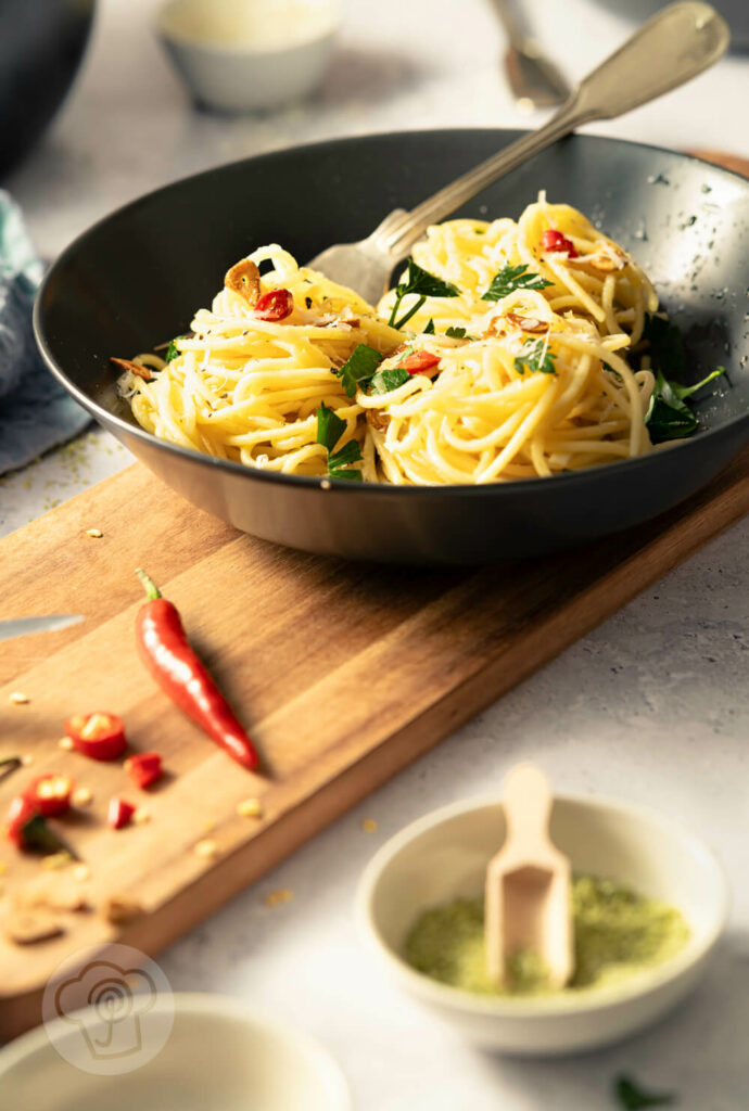 Spaghetti aglio e olio - der italienische Klassiker, auf dem Teller mit Chili, gerösteten Knoblauchscheiben und Petersilie