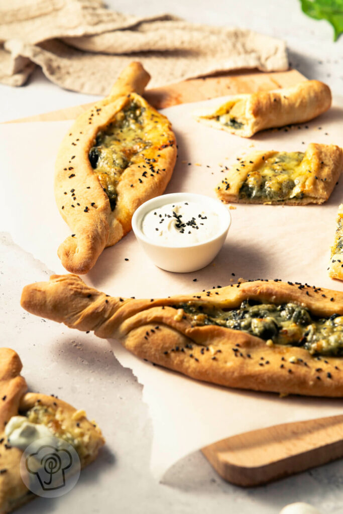 Vegane Pide mit Spinat und Joghurt auf einem Brett