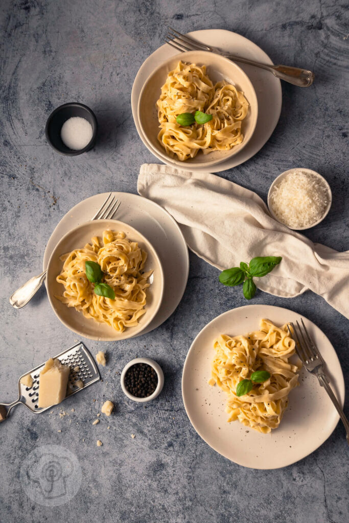 Schnelle Fettuccine Alfredo - Gericht aus 3 Zutaten 2 Fettuccine Alfredo mit Parmesan mehrere Portionen auf Tellern