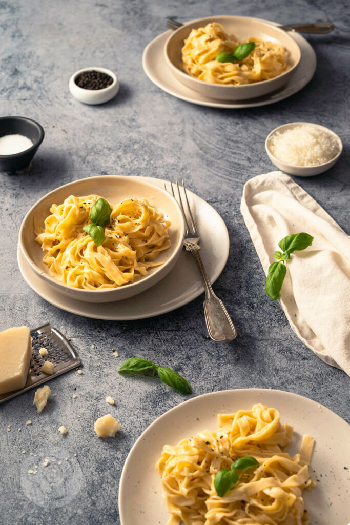 Schnelle Fettuccine Alfredo - Gericht aus 3 Zutaten 6 Fettuccine Alfredo mit Parmesan mehrere Portionen auf Tellern